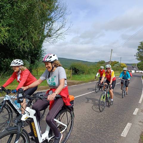 Several women cycling along a minor road.