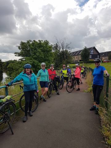 Cyclists posing on riverside cycle path.