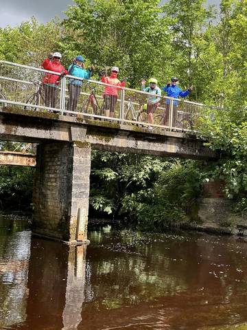 Cyclists posing on bridge above river.
