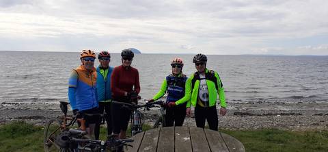 Cyclists posing on Girvan beach with Ailsa Craig in background.