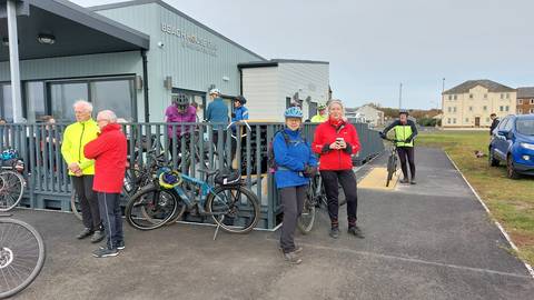 Several cyclists standing around at cafe building.
