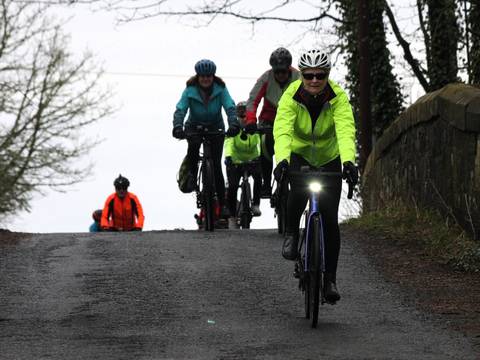 Cyclists appear over a rise.